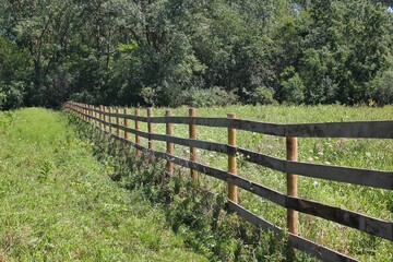 Fototapeta na wymiar Traditional wooden boundary fence running thru the local farm fields.