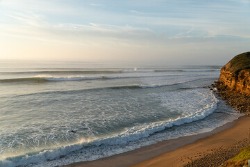 Sunrise at Bells Beach, Victoria, Australia with waves breaking in the surf and surfer on wave