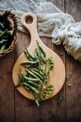 rounded wooden cutting board top view. wooden cutting board with young green peas on it. concept of wood board and seasonal fresh vegetables.