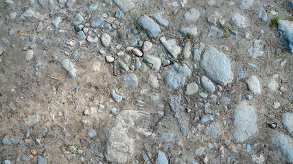 Close up unpaved road surface, stones and sand.