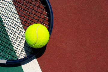 Tennis racquet and ball lying on the court. Space for text