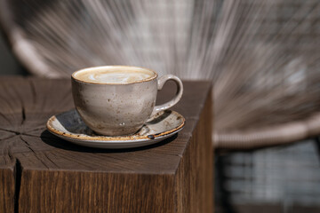 Cup of black coffee with milk in beige craft cup on a solid wood oak coffee table