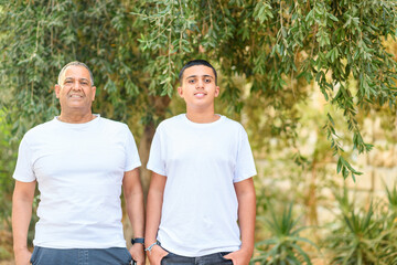 Teenager son and senior father standing outdoors.