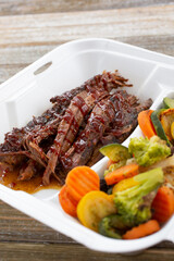 A view of a to-go container of BBQ brisket.