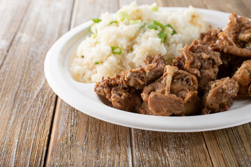 A view of a plate of chicken adobo and fried rice.