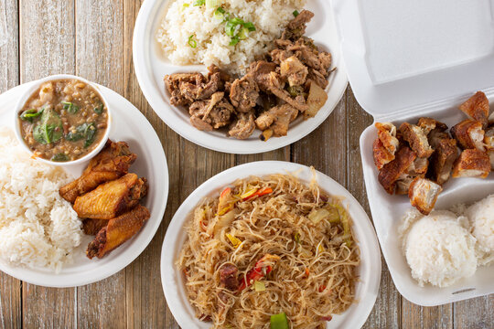 A top down view of several Filipino entrees on a wood surface.