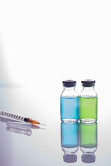 close-up vaccine. Glass vials with multi-colored liquid and a syringe, on a white background.