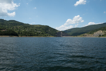Beautiful Zavojsko jezero (Zavoj lake) view over the wavy water with sunlit mountains and green forests on the other side and rafts in the water