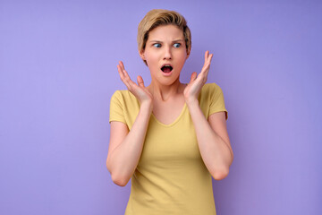 portrait of attractive lovable cute worried nervous , shocked short-haired caucasian woman having panic expression isolated over purple pastel color background, copy space. human emotions concept.