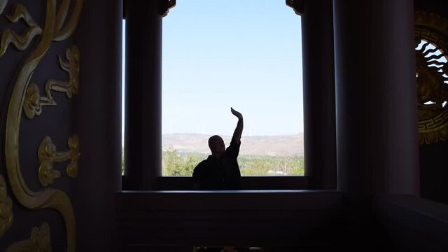 Kung Fu Master Is Doing Breathing Practice At A Large Window. Silhouette Of An Old Man Who Is Doing In Martial Arts