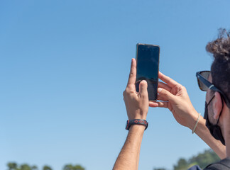 Una hombre con gafas de sol sacando una foto con el movil en un dia despejado