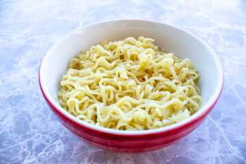 Instant noodle in red bowl on marble background.