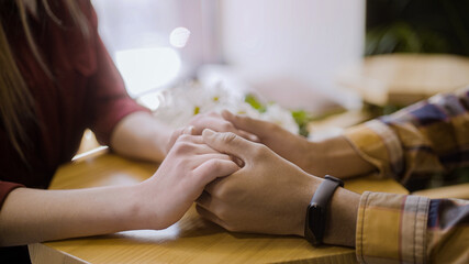 Close-up of man taking beloved girlfriend by hands in cafe, romantic date