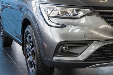 Renault Arkana gray SUV at Renault showroom. Close-up of right headlight, right front fog lamp and right front wheel. Renault car dealership in Mega Adygea. Krasnodar, Russia - August 17, 2021 - Powered by Adobe
