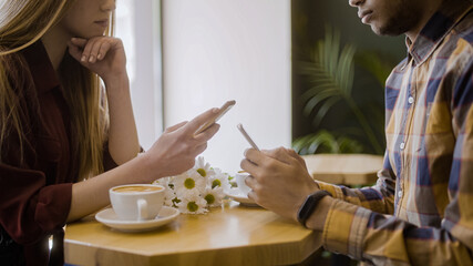 Mixed-race couple browsing gadgets on date, addiction to social media problem