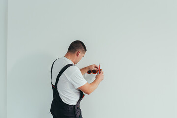 Male worker professional electrician installs electrical outlet in apartment after repair
