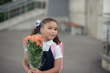 Fototapeta premium A girl in a blue school dress and dark shoes with a pink backpack. Copy space.