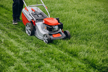 Fototapeta na wymiar Man cutting grass with lawn mover in the back yard