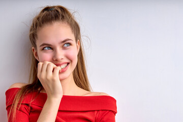 Beautiful dreamy caucasian female girl looking at side and smiling, isolated on white background, copy space. Attractive lady in red shirt posing, thinking about something, looking cutely