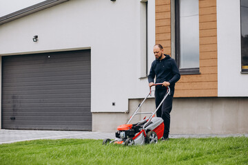 Man cutting grass with lawn mover in the back yard
