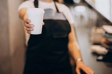Female barista holding cardboard coffee cup