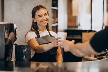 Female barista giving coffee to the customer