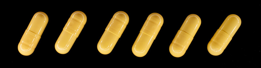 yellow pills in a capsule on a black, rough background, macro photo