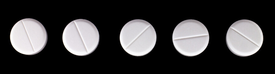 white, round pills on a black background. macro photo