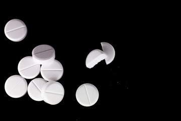 white, round pills on a black background. macro photo