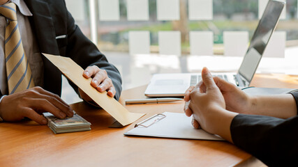 A businessman is presenting a hundred dollar bill in an envelope to an officer. hand close up Concepts of evil, bribes, corruption, giving money - US dollars in the office.
