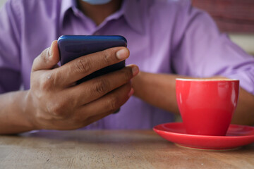  young man hand using smart phone with tea and cookies on table 