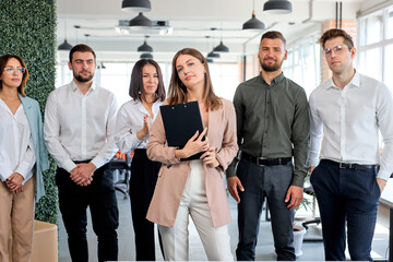 Portrait Of Young Caucasian Business Team In The Head Of Beautiful Lady Posing At Camera, Looking Nice And Affable. Confident Managers And Leaders In Bright Modern Office, At Business Meeting