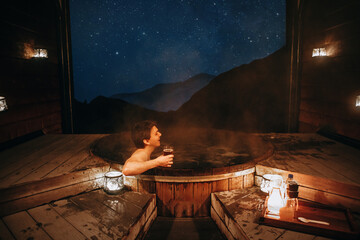 Man relaxing with a cherry in his hands at an Hot Pools in Queenstown at night. New Zealand - obrazy, fototapety, plakaty