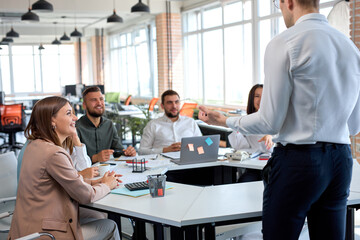 friendly nice business leader manager having talk, giving speech to colleagues. Young guy in formal wear suit gesturing, explaining business strategy and sharing ideas, focus on male hands