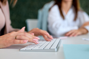 Business innovation and digital technologies.Young hardworking cropped businesswoman sitting in modern bright office and using computer. Corporate business concept, close-up female hands, copy space