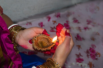 Hands of an Indian woman holding Diya or Pradip ( oil lamp ) on Diwali festival. Selective focus on...