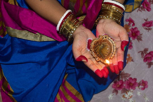 Hands of an Indian woman holding Diya or Pradip ( oil lamp ) on Diwali festival. Selective focus on Pradip. Concept of celebrating the Deepavali festival.