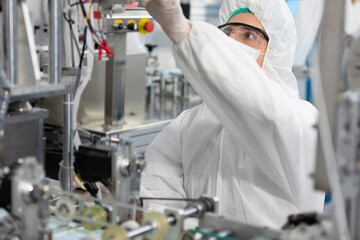 male engineers wearing personal protective equipment uniform(PPE) and medical face mask, checking machine in laboratory