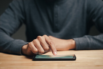 Closeup of a man using a smartphone on the wooden table, searching, browsing, social media, message, email, internet digital marketing, online shopping..