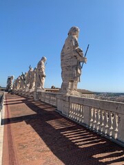 White marble, stone statues, sculptures on the roof of Saint Peter's Basilica church. Panoramic view of Roma city. Vatican city, Vatican, Rome, Italy.