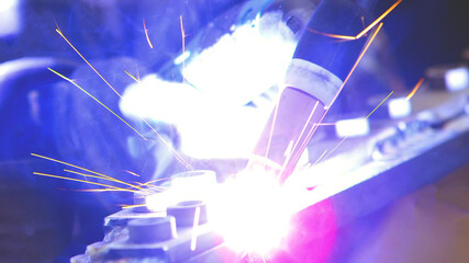 Gas tungsten arc welding GTAW torch, close up of weld electrode on metal sparks light background. - 452167722