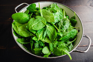 Fresh Baby Spinach Leaves in a Colander: A metal colander filled with fresh baby spinach leaves