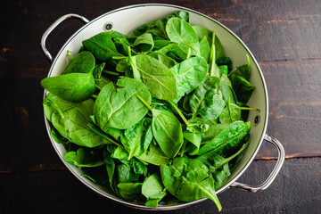 Fresh Baby Spinach Leaves in a Colander: A metal colander filled with fresh baby spinach leaves
