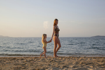 Fototapeta na wymiar Mother and daughter walking on the beach. Family summer vacation concept. 