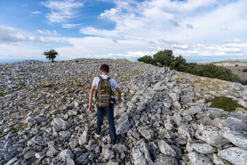 Fototapeta na wymiar Rear view of a teenager boy hiking through a rocky field