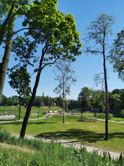 View of the roads and the observation deck with white benches in the Summer Garden of the city of Kronstadt against the background of a blue cloudless sky.
