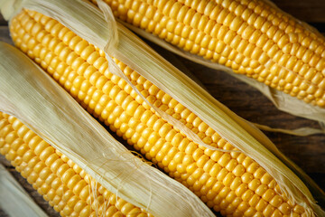 Fresh corn on the cob on a rustic wooden table, close up.