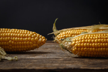 Fresh corn on the cob on a rustic wooden table, close up.