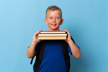 school, education and people concept - portrait of smiling little student boy in blue t-shirt with books over blue background