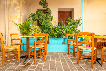 Fototapeta na wymiar Tables and chairs in an atmospheric place with a nice atmosphere, among greenery, blue pots and medieval walls
